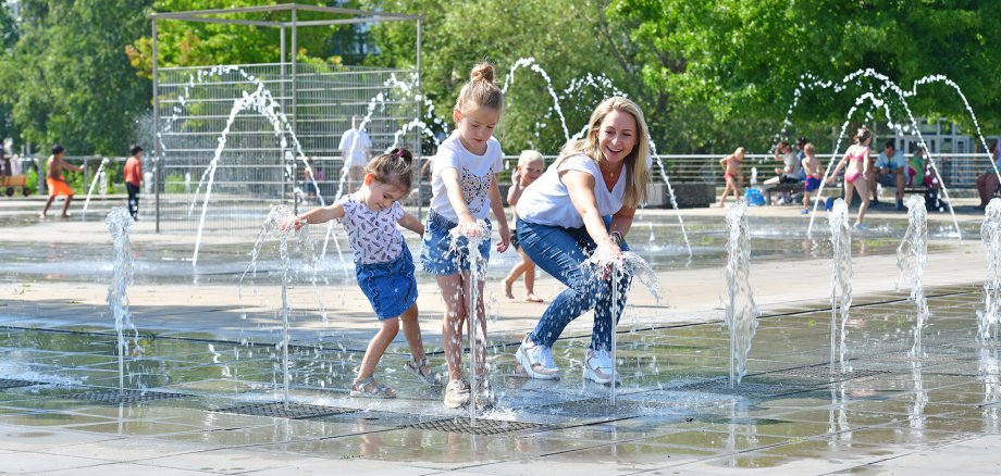 Kinder springen im Wasserlabyrinth durch die Fontänen