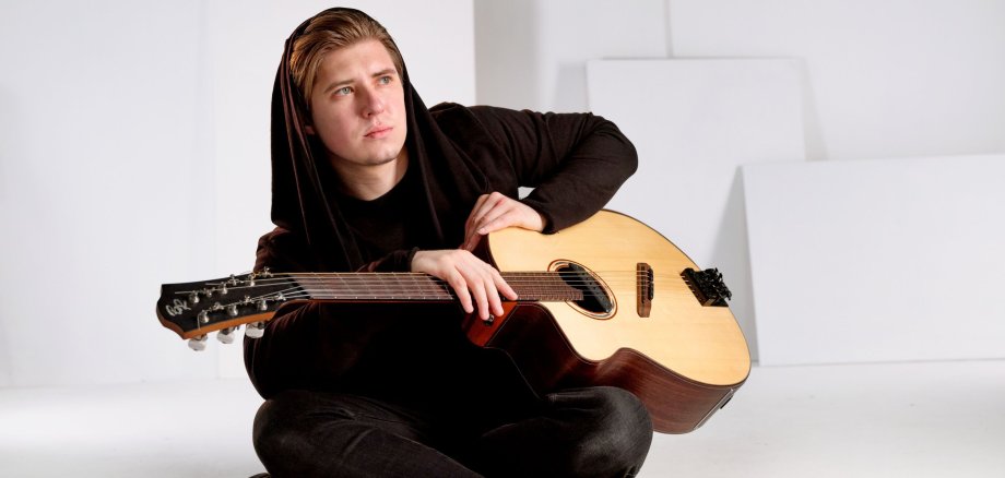 Alexandr Misko mit einer Gitarre in der Hand.