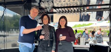 Eine Besucherin und zwei Angestellte am Stand des Weinservices Steillage 