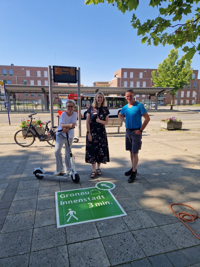 Mitarbeitende des Stadtmarketing und der Zentralen Bau- und Umweltdienste vor einem neuem Piktogramm als Hinweis zur Innenstadt