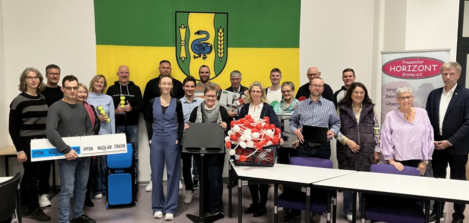 Gruppe von Personen im Ratssaal der Stadt Gronau vor dem Wappen